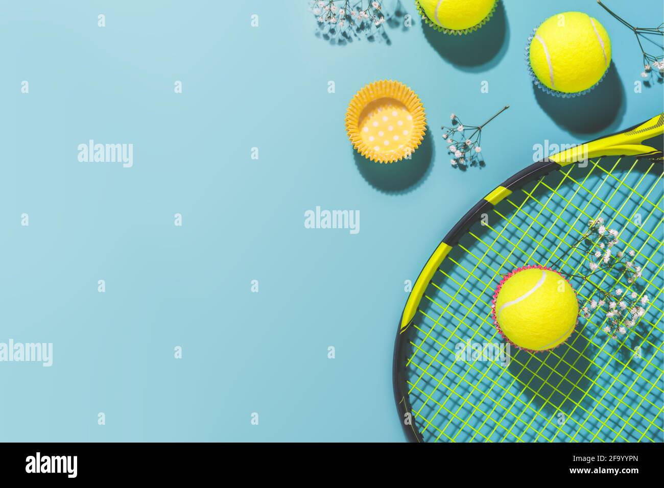 Festa di tennis. Composizione sportiva Holliday con palla da tennis gialla e racchetta su sfondo blu di campo da tennis duro Foto Stock
