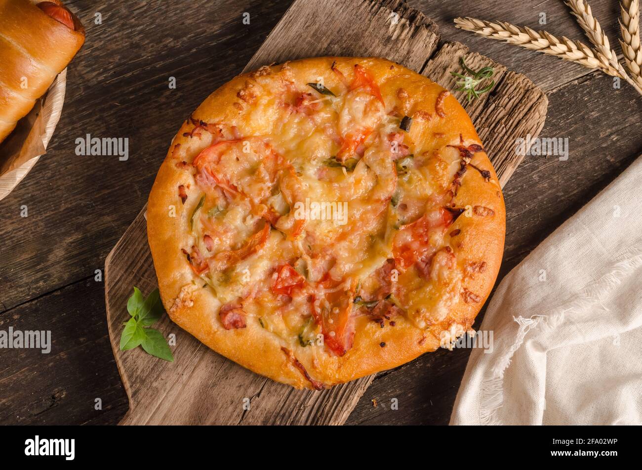 Pizza con formaggio e pomodori su sfondo ligneo da vicino con ingredienti Foto Stock