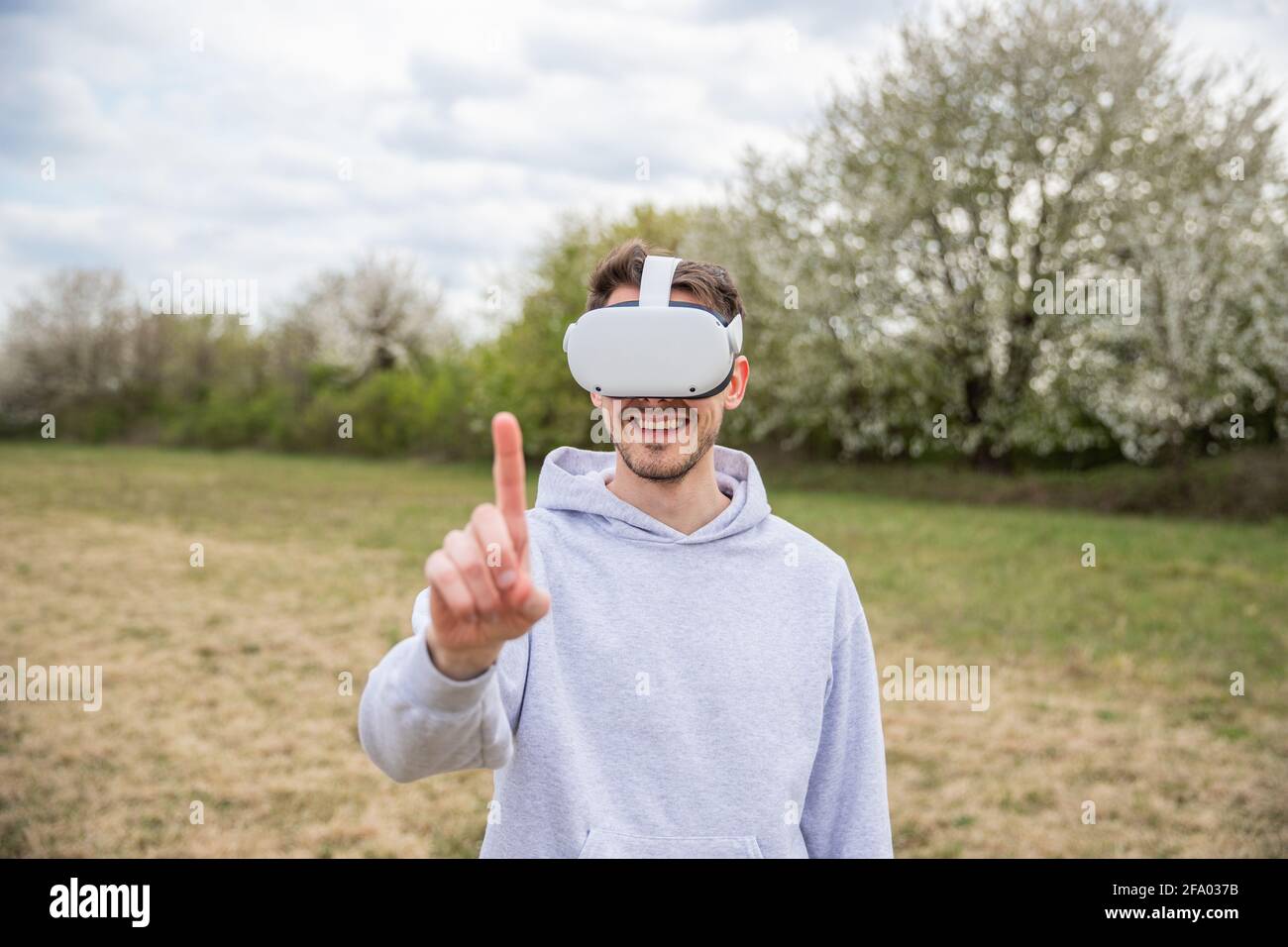 Un ragazzo in un campo si diverte mentre usa alcuni visori per la realtà virtuale all'aperto in un campo. Foto Stock