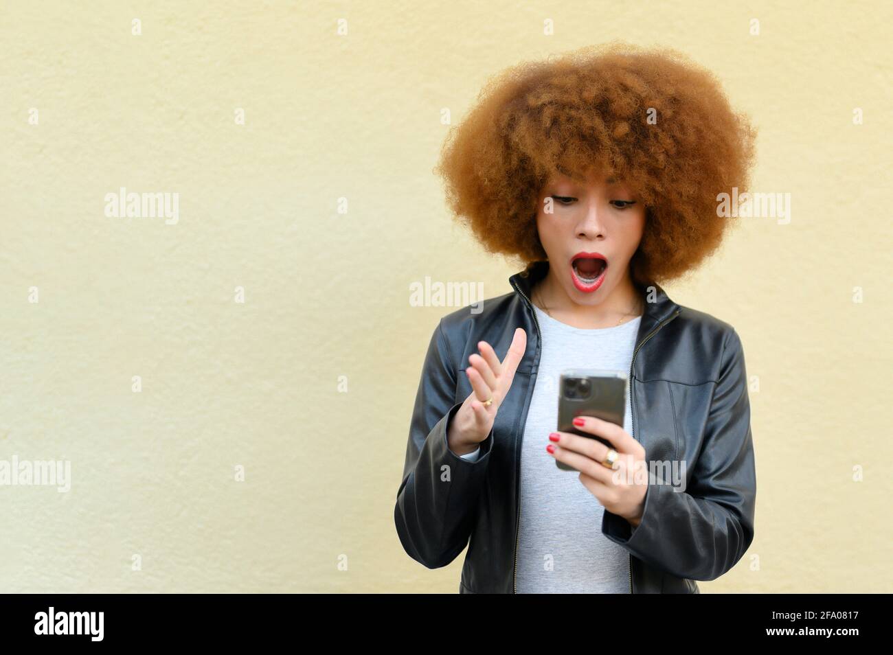 donna a bocca aperta che guarda il suo telefono Foto Stock