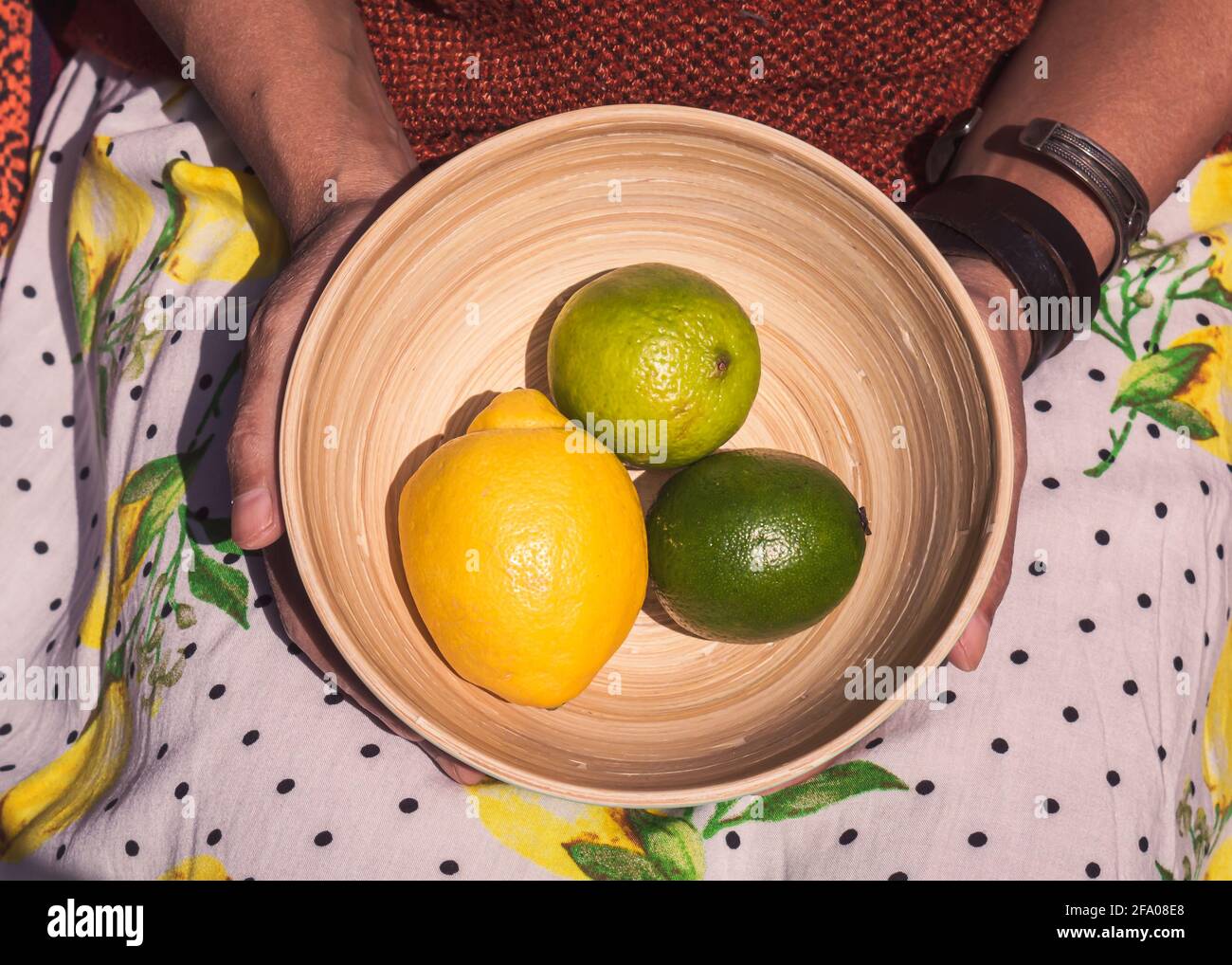 Donna di colore che tiene una ciotola di bambù con limone e. due lime Foto Stock