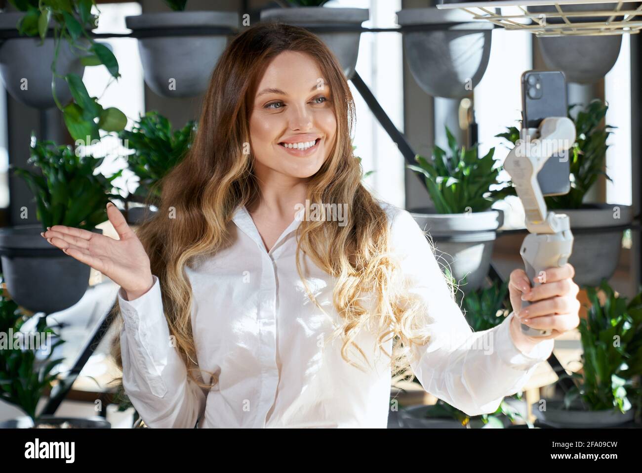 Primo piano ritratto di felice attraente giovane donna sorridente e comunicante per telefono con i seguaci dei social media. Concetto di processo che parla online con gli abbonati di buon umore. Foto Stock