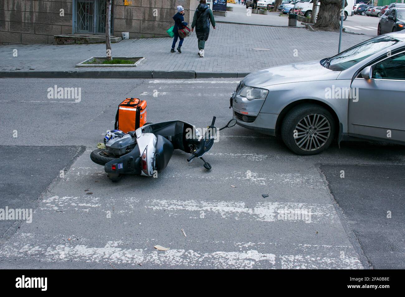 Dnepropetrovsk, Ucraina - 04.21.2021: Casco e moto dopo un pericoloso incidente stradale con una macchina sulla strada. L'uomo di consegna del cibo wa Foto Stock