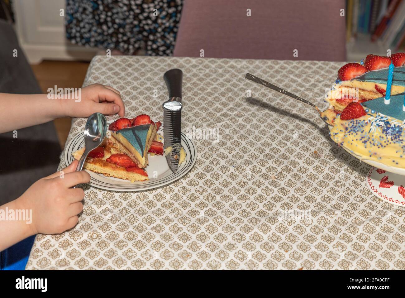 Primo piano vista delle mani del bambino con cucchiaio pronto a mangiare torta di compleanno. Svezia. Foto Stock