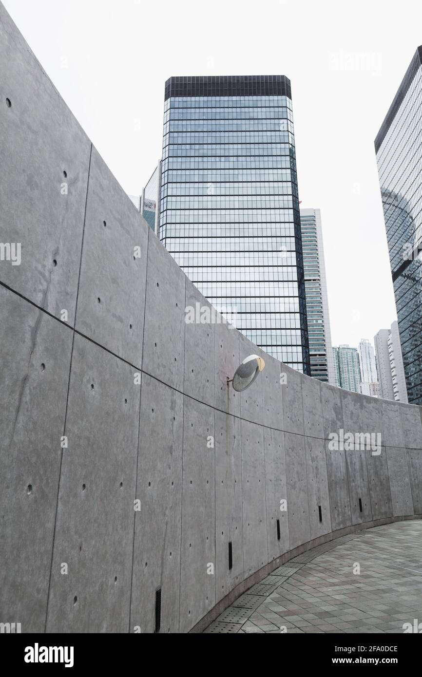 Moderna vista sulla via vuota della città con pareti in cemento e grattacieli sullo sfondo, alti edifici per uffici di Hong Kong Foto Stock