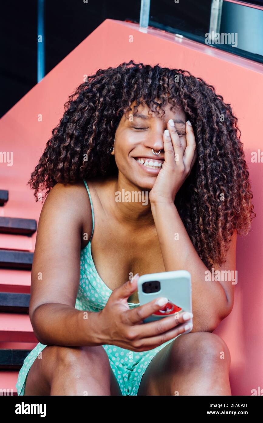 Sorridente donna africana utilizzando il suo smartphone Foto Stock