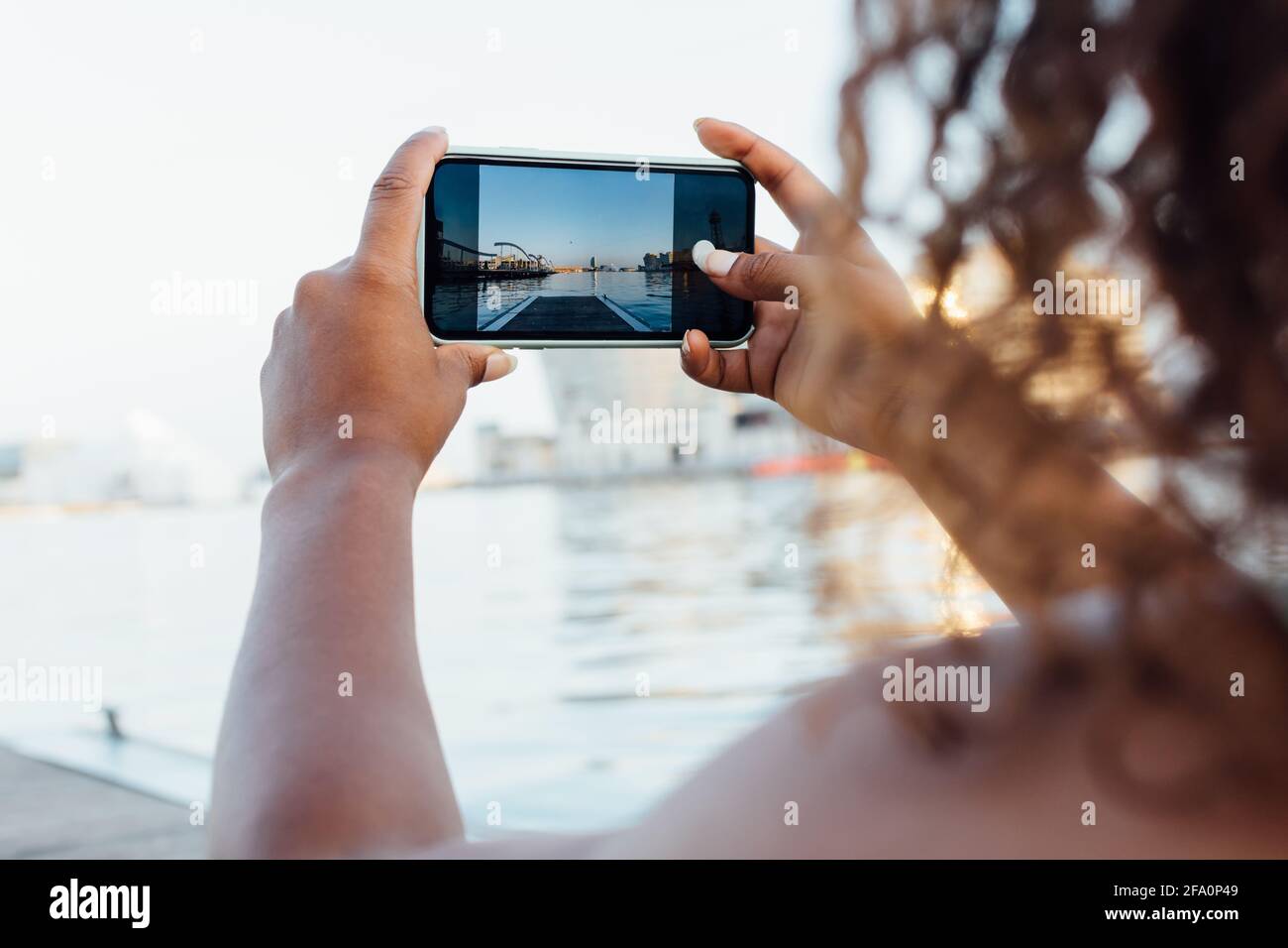 Primo piano di una donna africana che prende una foto con lei smartphone al mare Foto Stock