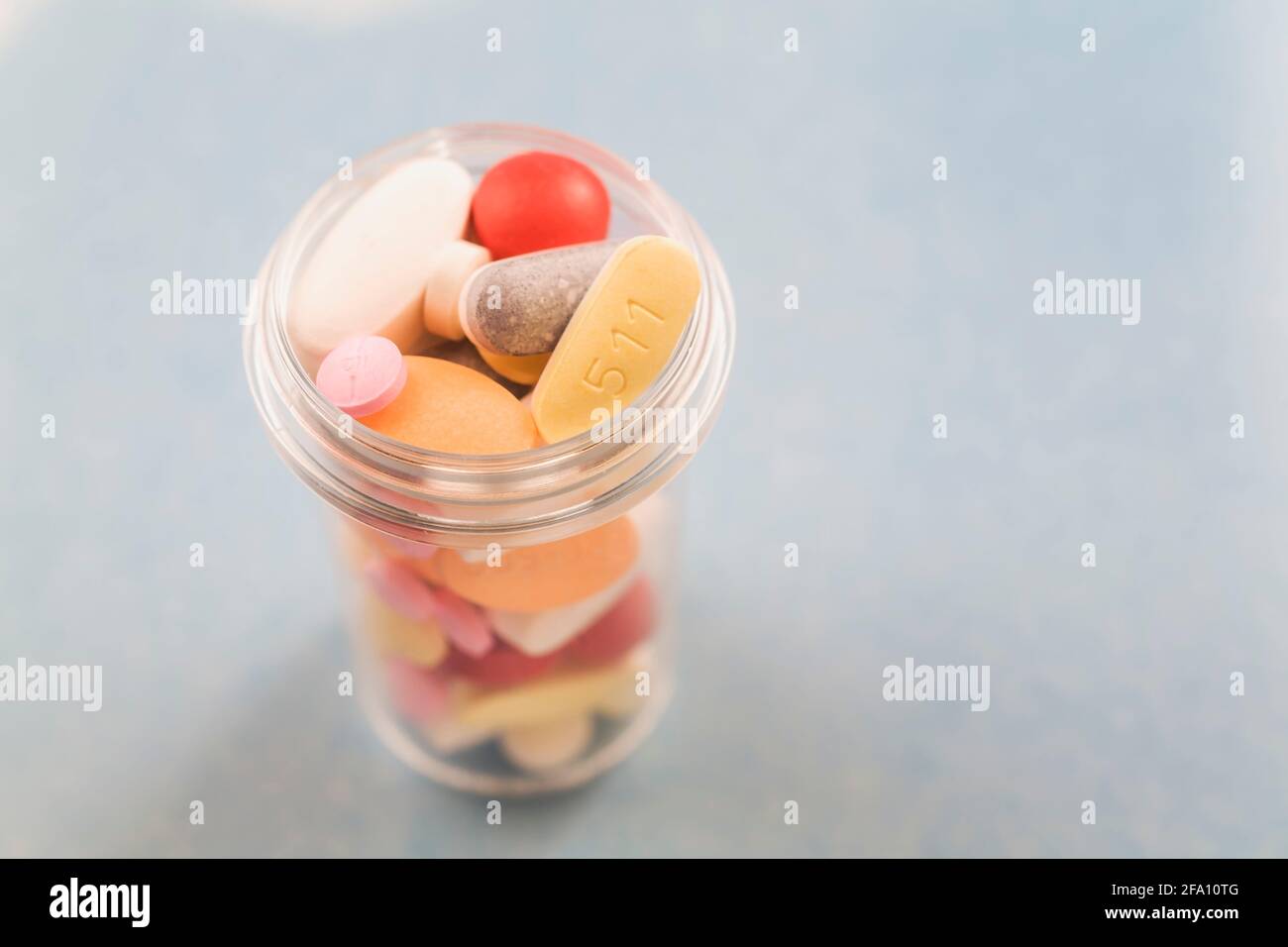 Pillole di medicina assortite in bottiglia rotonda di plastica su sfondo grigio Foto Stock