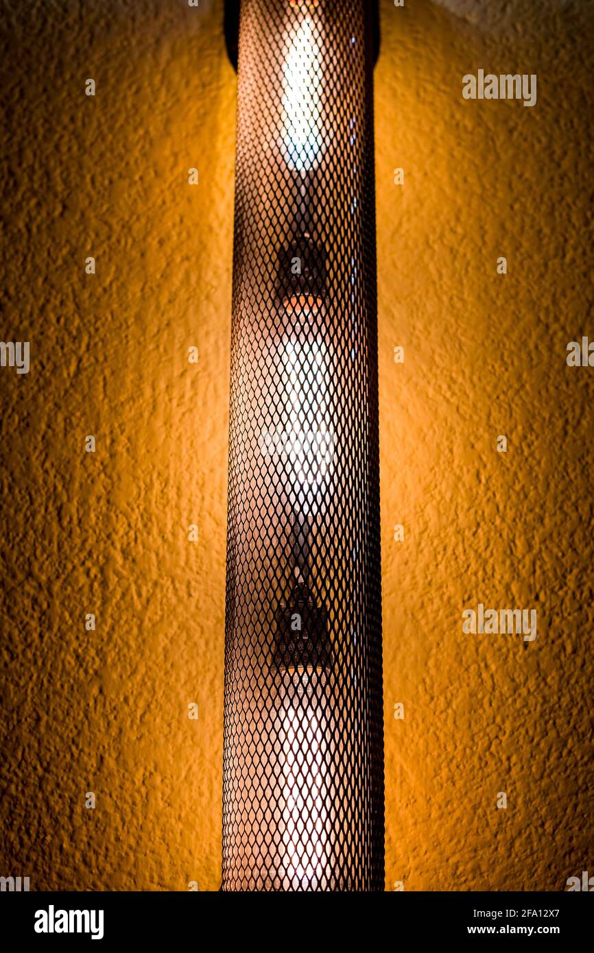 loft stile lanterna stradale tubo a traliccio esagonale con luce edison bulbo sulla facciata di un edificio con stucco giallo primo piano della luce architettonica Foto Stock