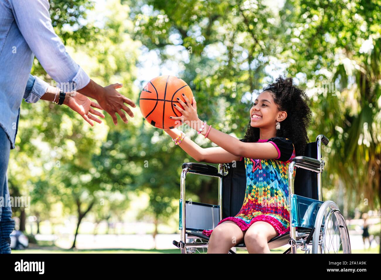 Bambina in sedia a rotelle che gioca a basket con suo padre. Foto Stock