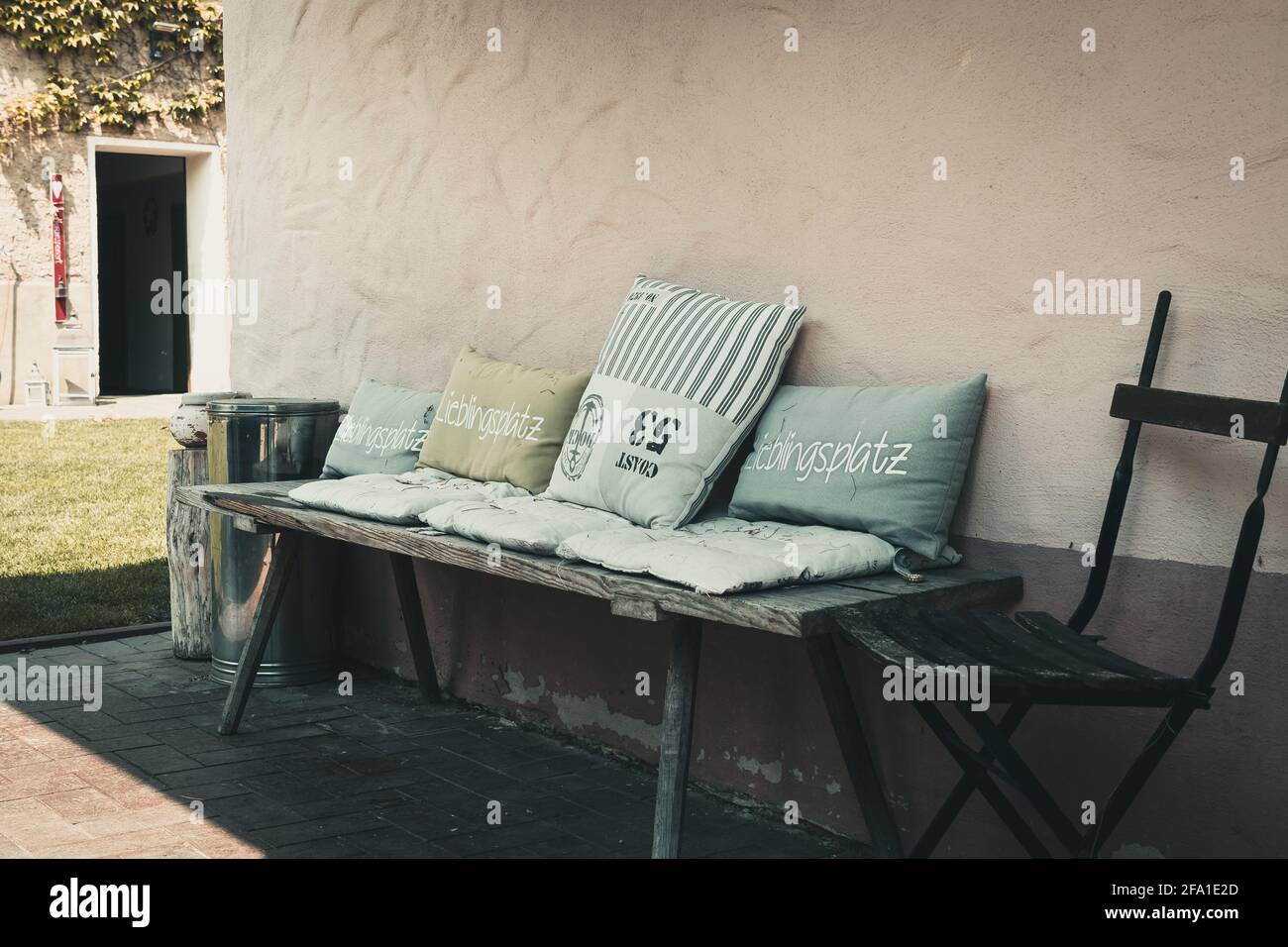 Panca rustica in legno con diversi cuscini, aspetto vintage. L'iscrizione 'Lieblingsplatz' (in tedesco) significa 'luogo preferito'. Foto Stock