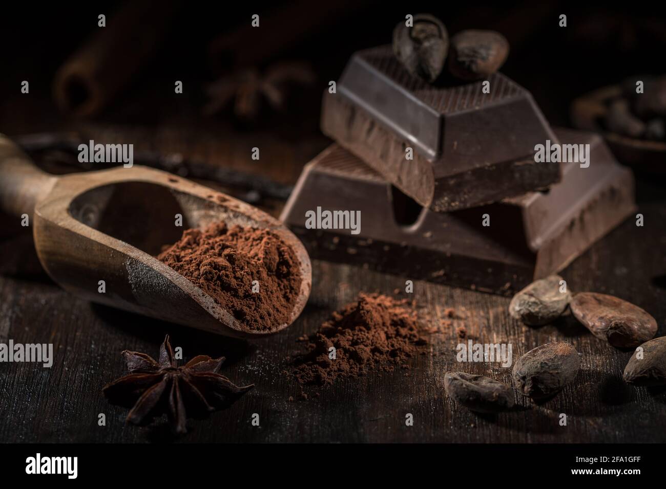 Paletta di legno con polvere di cacao e pezzo di cioccolato a blocchi con fagioli di cacao. Foto Stock