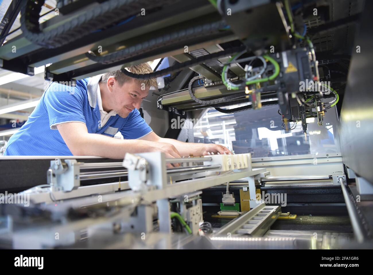 Ingegnere di lavoro su una macchina per il montaggio e la produzione di schede a semiconduttore in un impianto industriale Foto Stock