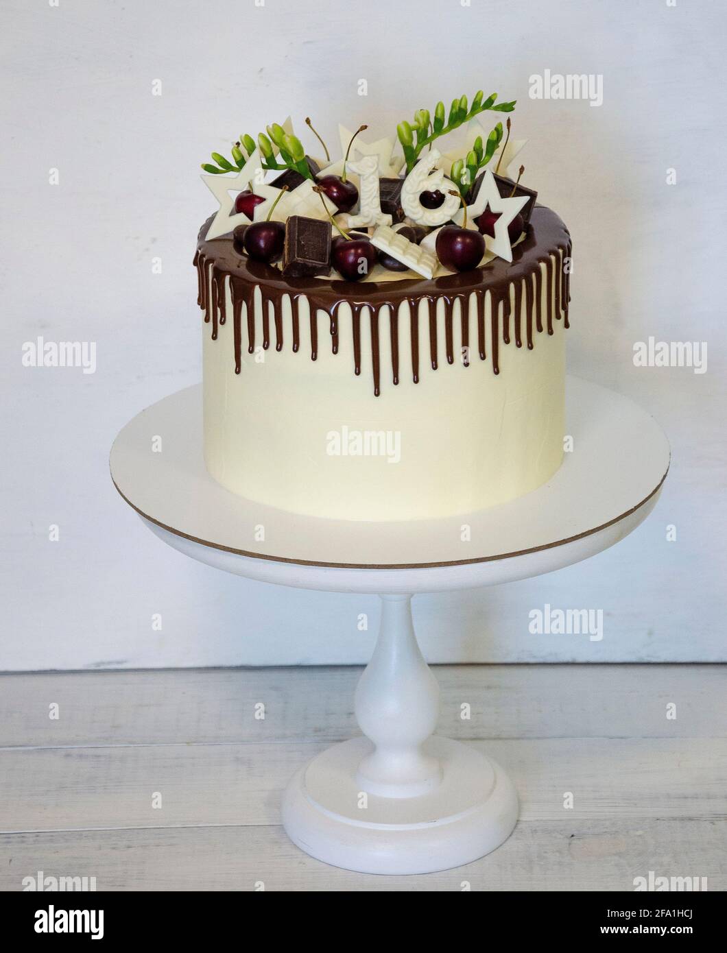 torta di compleanno con gocce di colore per il 16° anniversario con decorazione al cioccolato Foto Stock