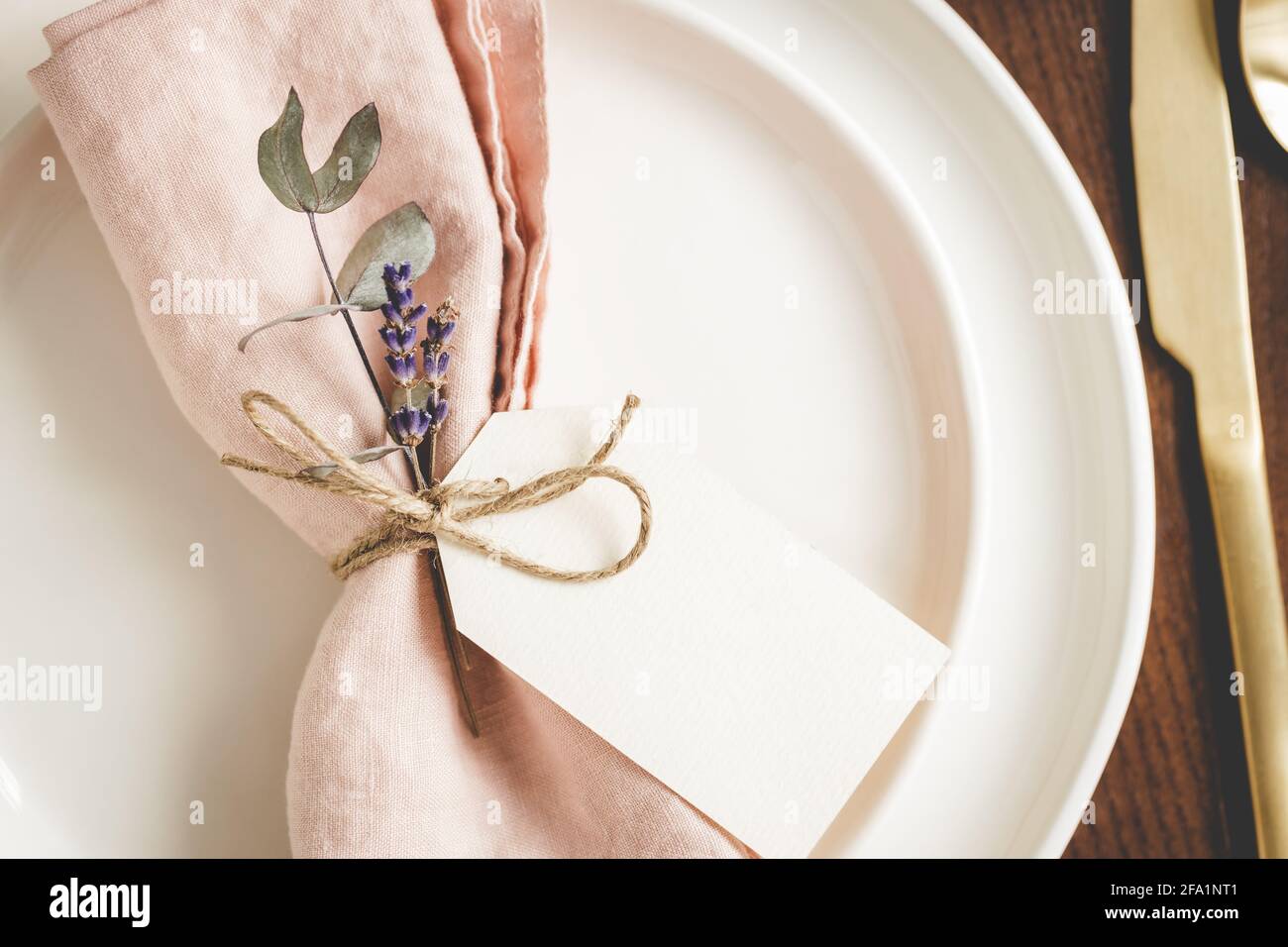 Primo piano vista su piatti disposti con un tovagliolo di lino rosa, decorazioni floreali e tag. Foto Stock