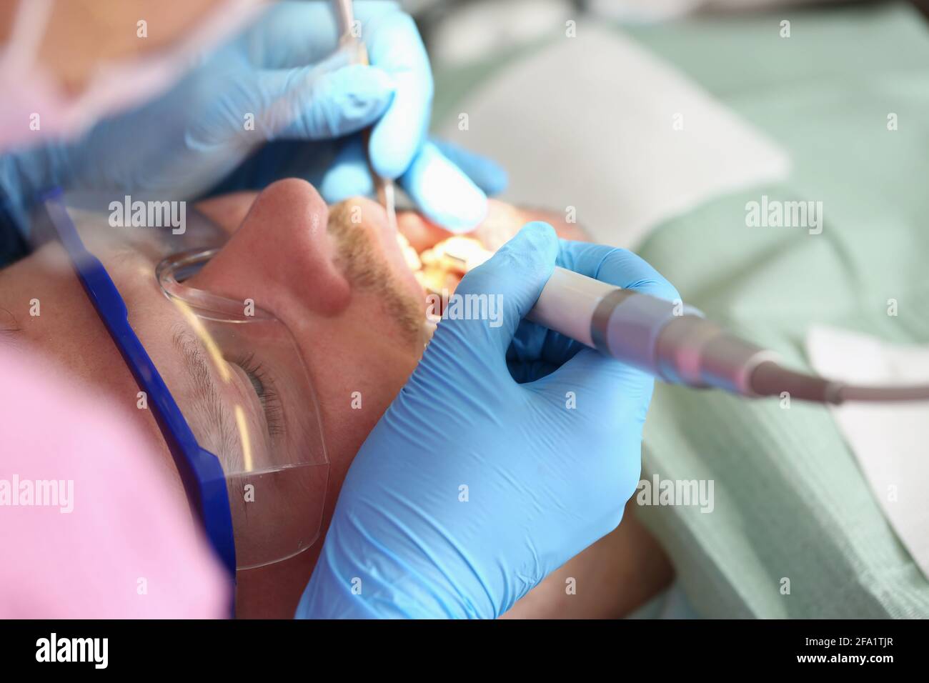 Medico dentista che cura i denti del giovane uomo nella clinica closeup Foto Stock