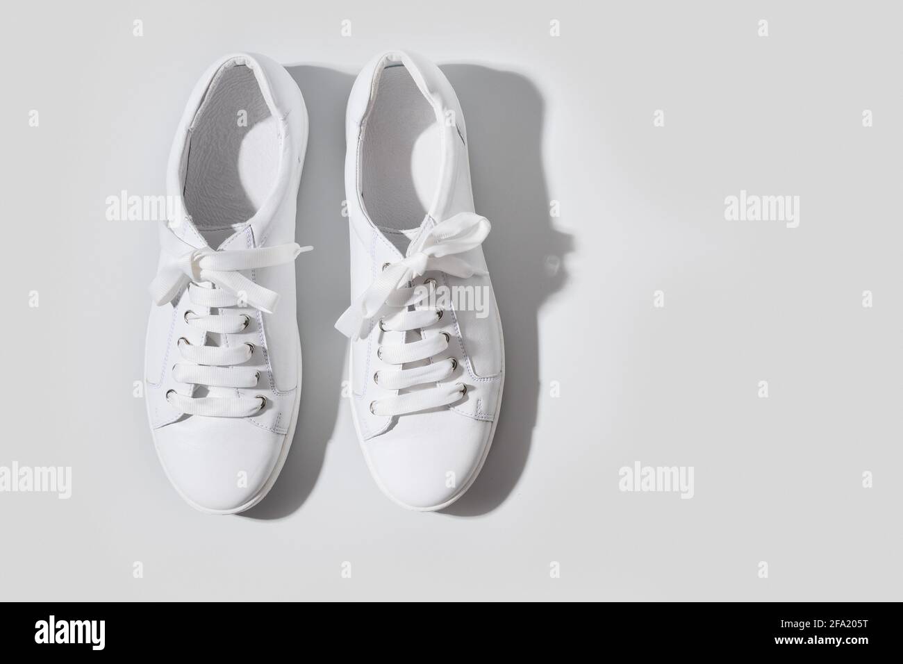 Scarpe da ginnastica bianche su sfondo grigio con spazio per la copia. Concetto di lavaggio e pulizia. Cura regolare delle scarpe. Vista dall'alto. Foto Stock