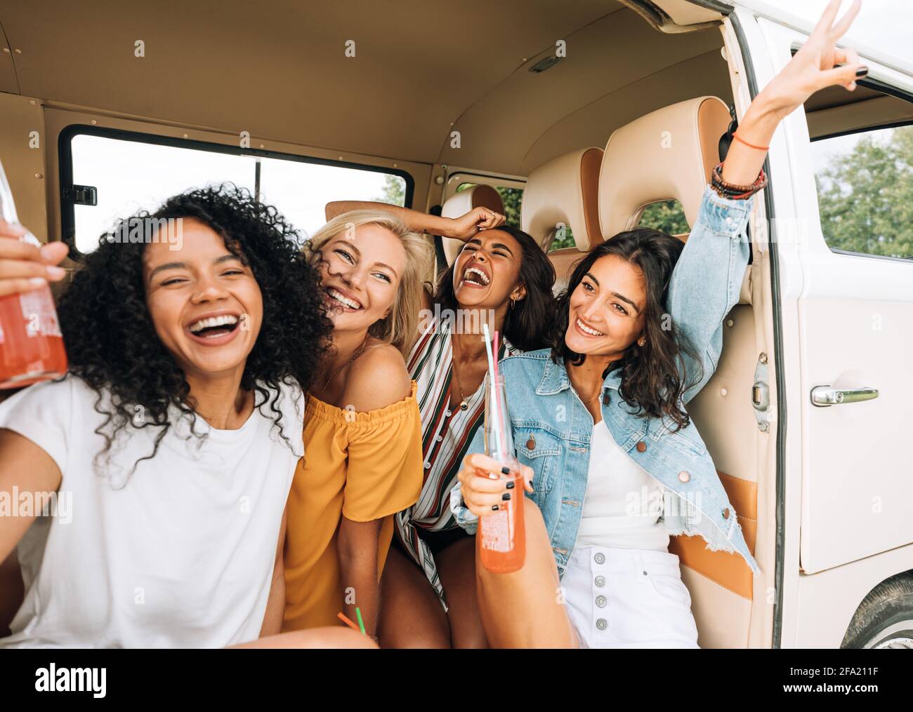 Quattro donne allegre godendo le vacanze seduti in camper tenuta cocktail Foto Stock