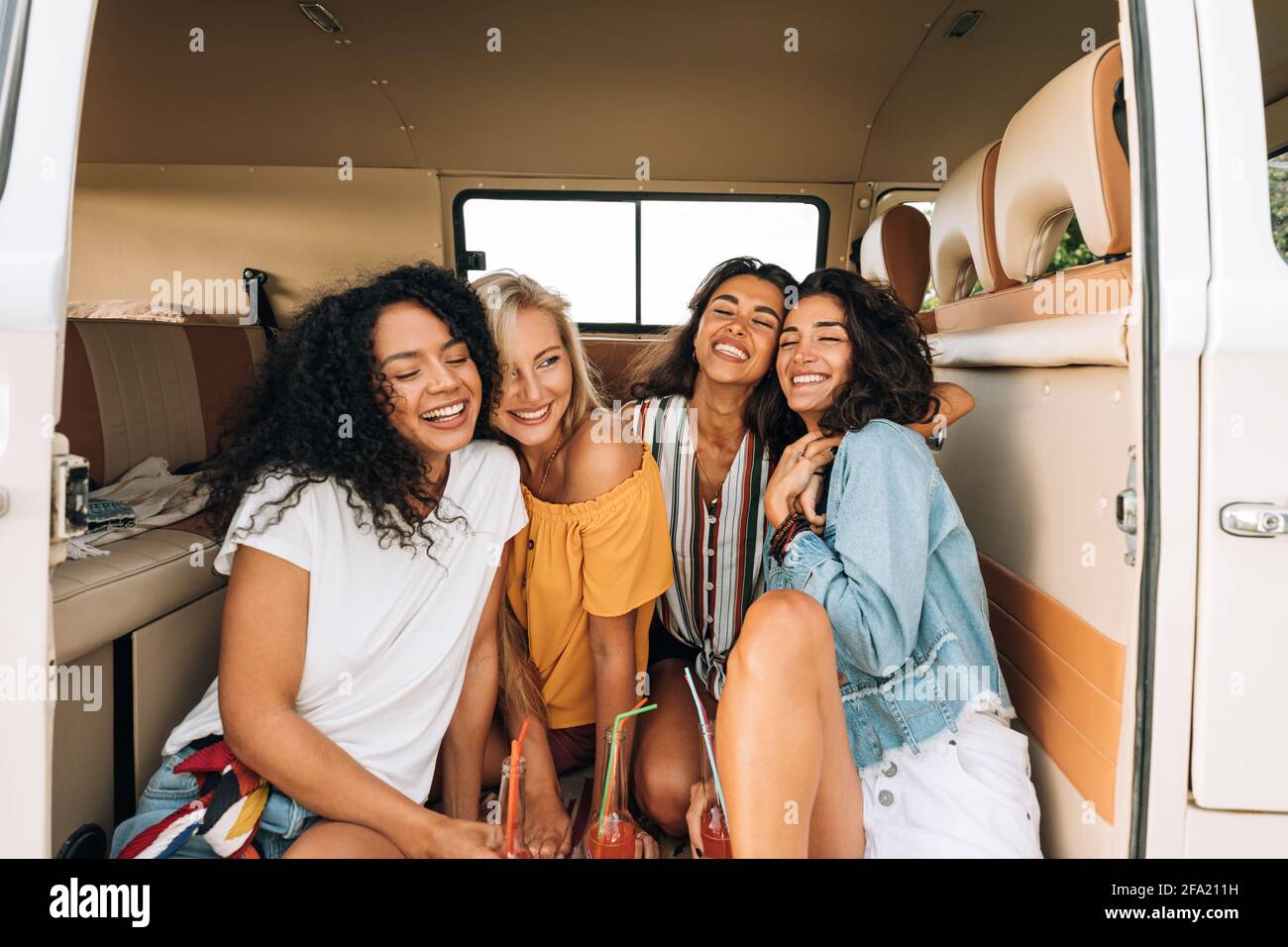 Felici le giovani donne che si siedono insieme in camper godendo la vacanza Foto Stock