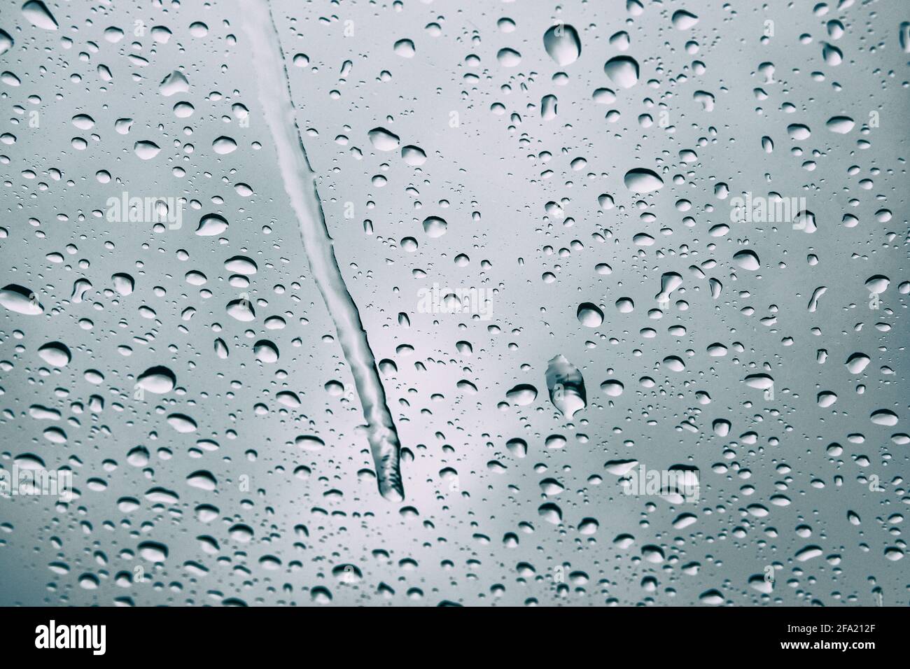Gocce di pioggia visibili sul finestrino. Giornata invernale in città. Giorno piovoso con tempo drammatico, a fuoco selettivo. Foto Stock
