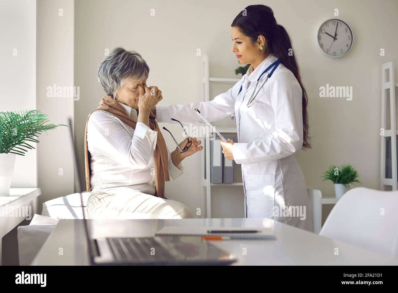 Donna anziana infelice con mal di testa o problemi di vista con cui parlare dottore in ospedale Foto Stock Donna anziana infelice con mal di testa o problemi di vista con cui parlare dottore in ospedale Foto Stock