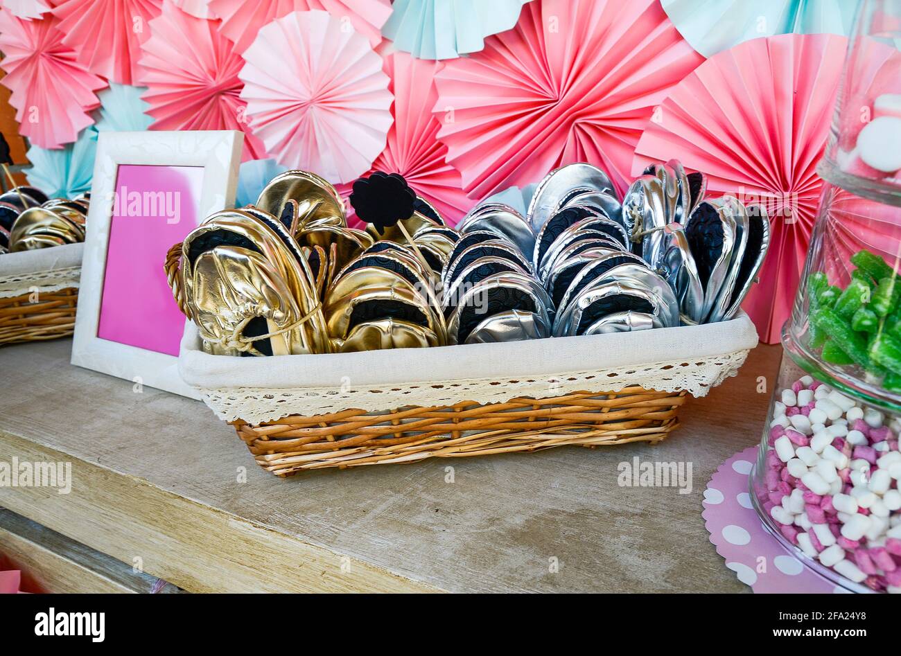Comode pantofole ripiegate per dare agli ospiti in un cestino su un tavolo decorato da festa. Foto Stock