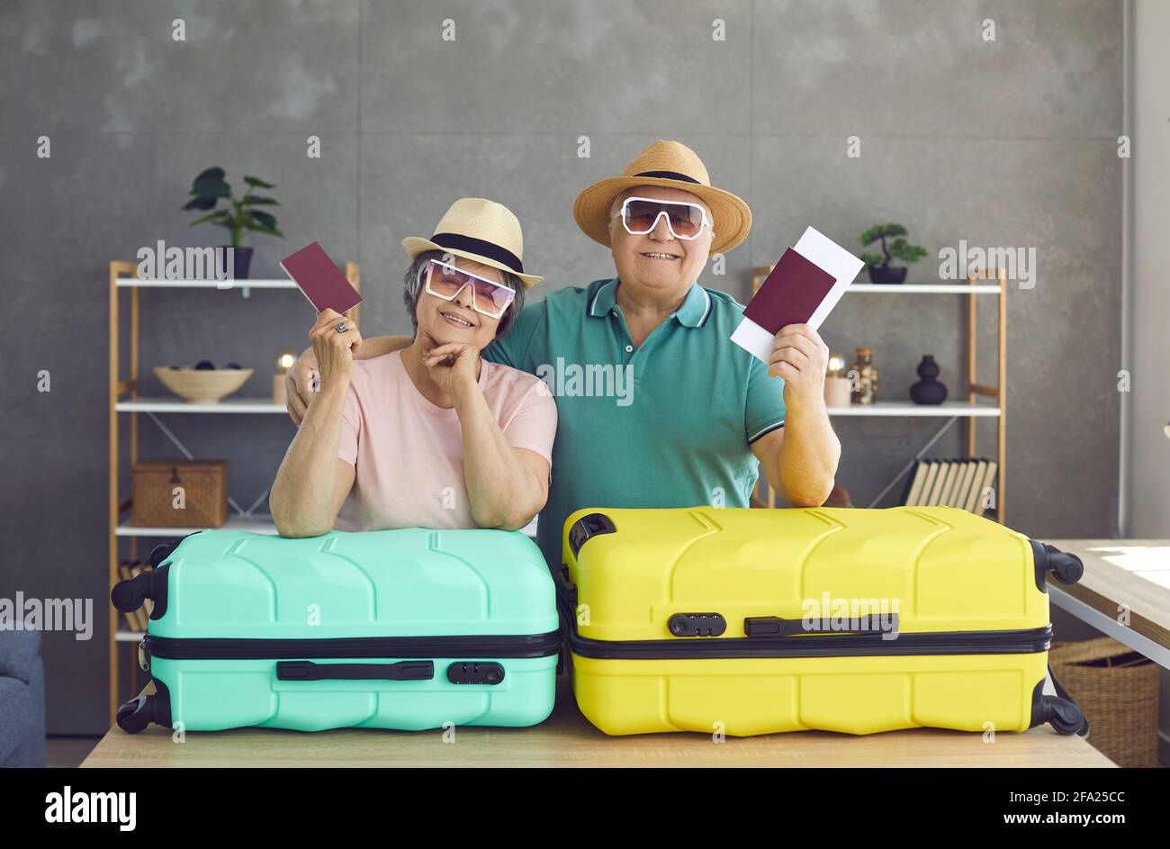 Ritratto di una coppia anziana allegra appoggiata su valigie che tengono passaporti e biglietti. Foto Stock