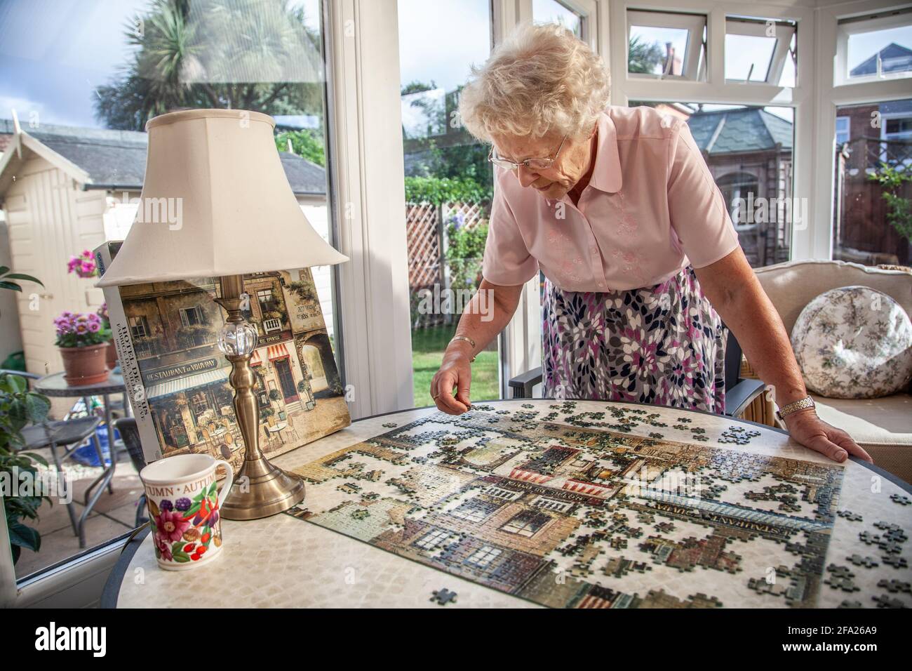 Donna anziana negli anni '70 che fa un puzzle a casa sua residenza, Inghilterra, Regno Unito Foto Stock