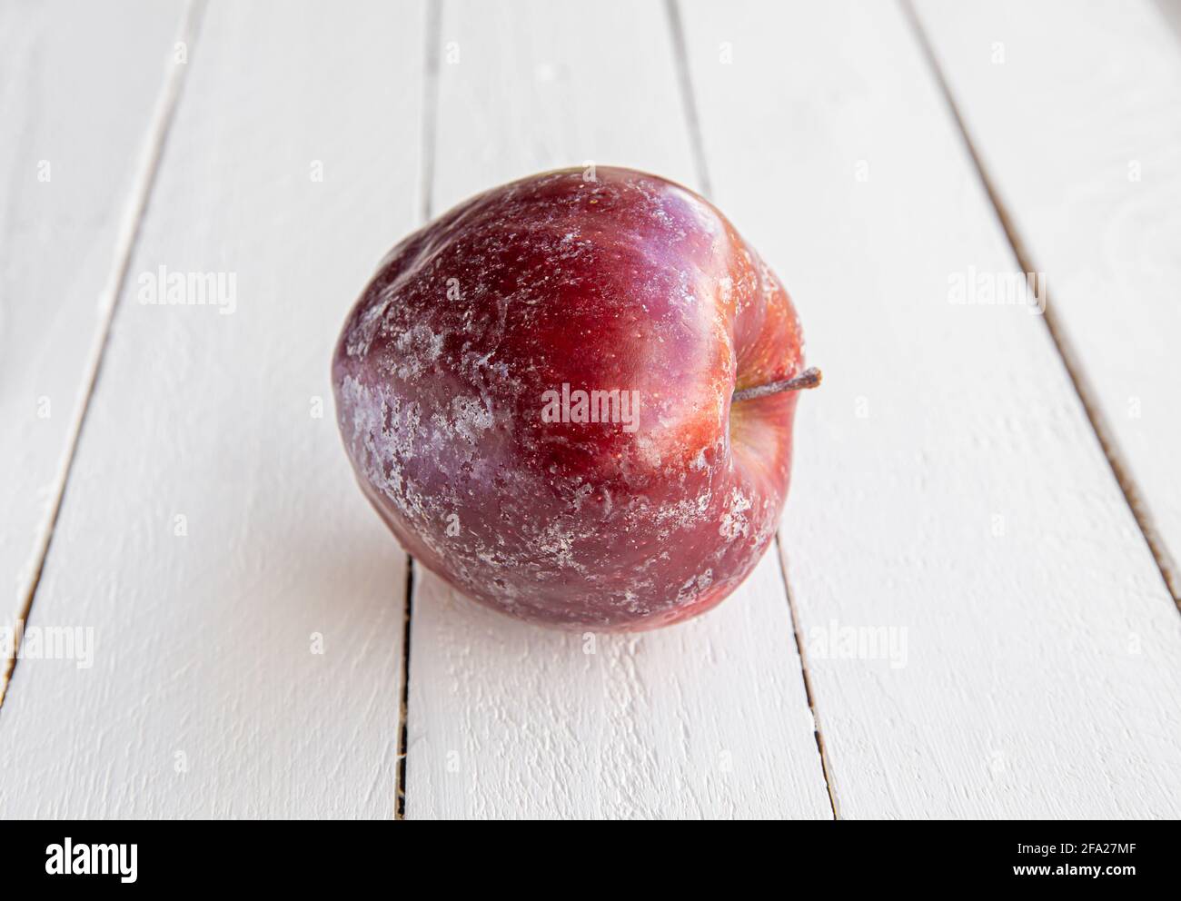 Mela rossa con strato bianco di cera protettiva che si scioglie parzialmente dopo aver lavato la mela a casa. Prima di vendere in negozio, applicano la cera. Foto Stock