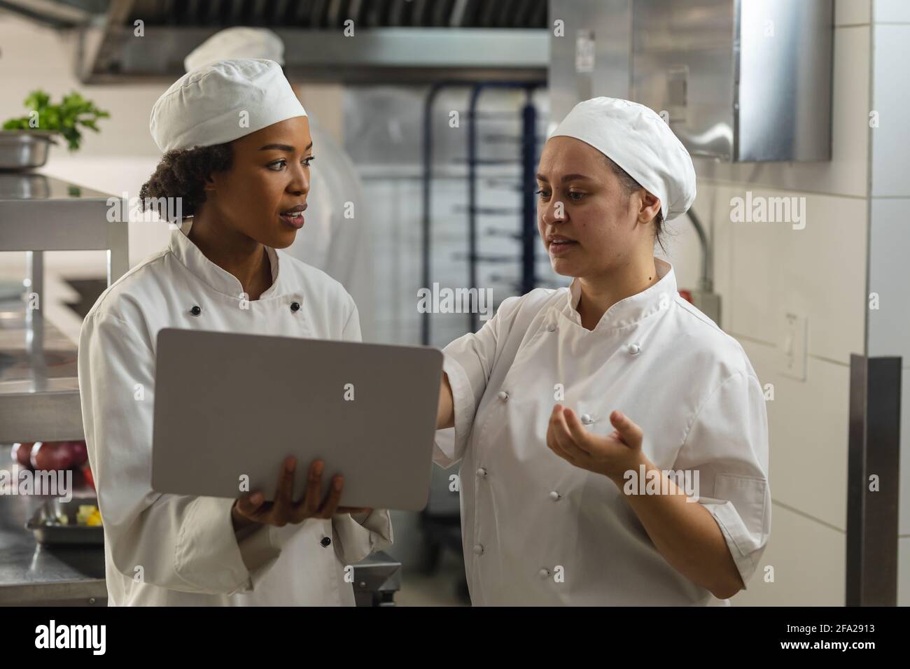 Ritratto di diverse donne di razza chefs professionisti discutisig su laptop Foto Stock
