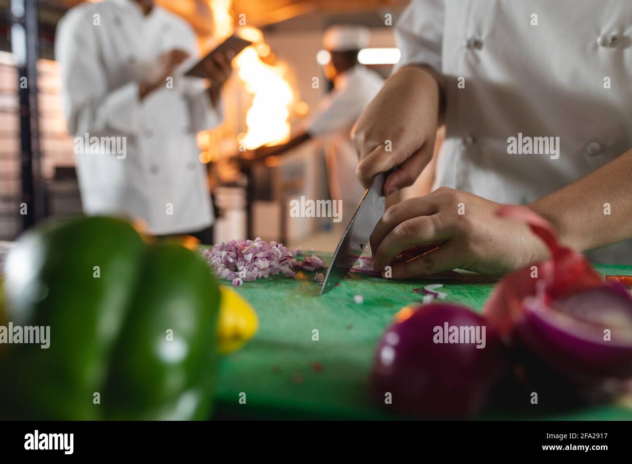 Sezione centrale dello chef professionista che prepara le verdure con un collega in background Foto Stock