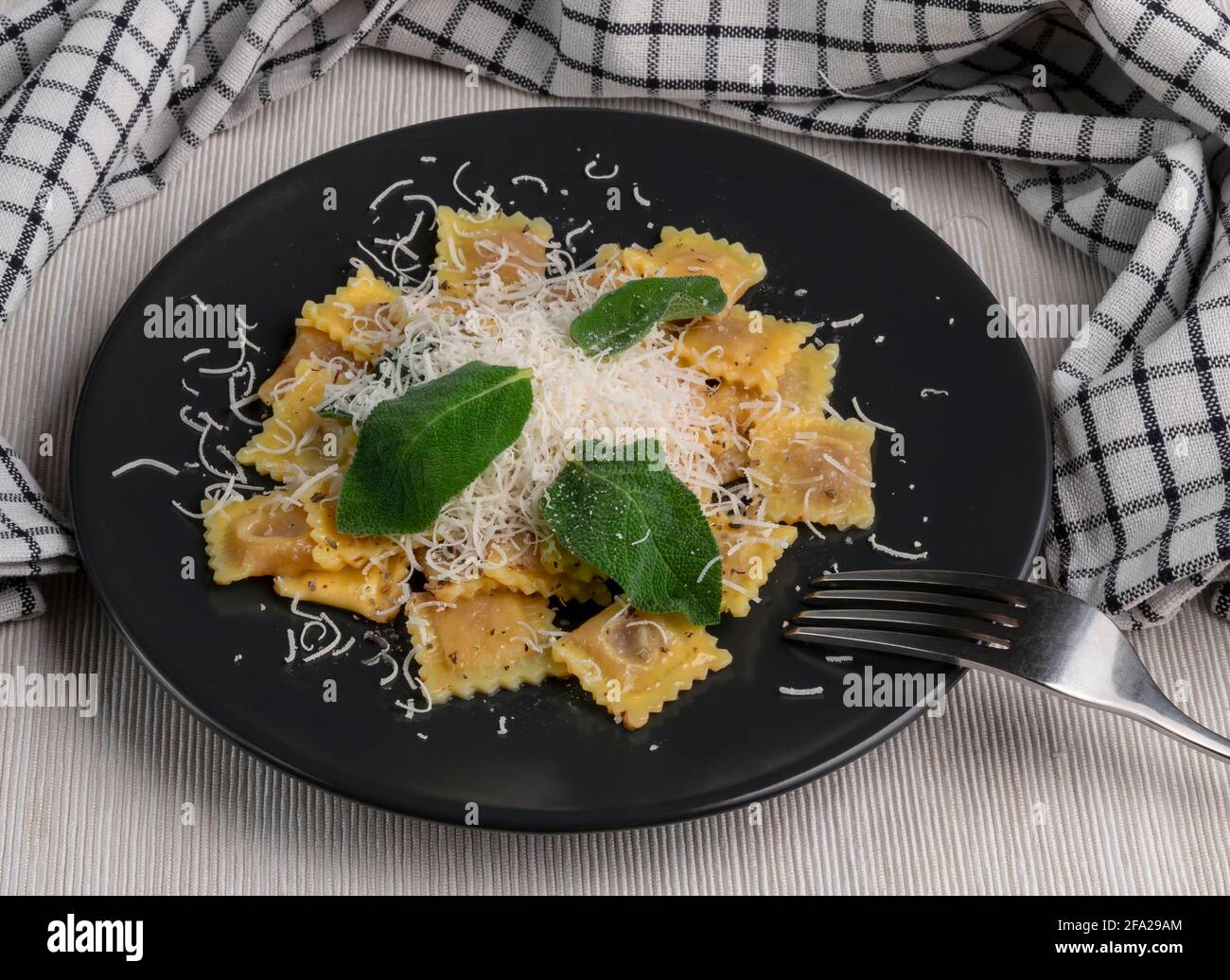 Un delizioso piatto di ravioli ripieni di carne con burro, foglie di salvia e parmigiano grattugiato, tipico piatto italiano Foto Stock