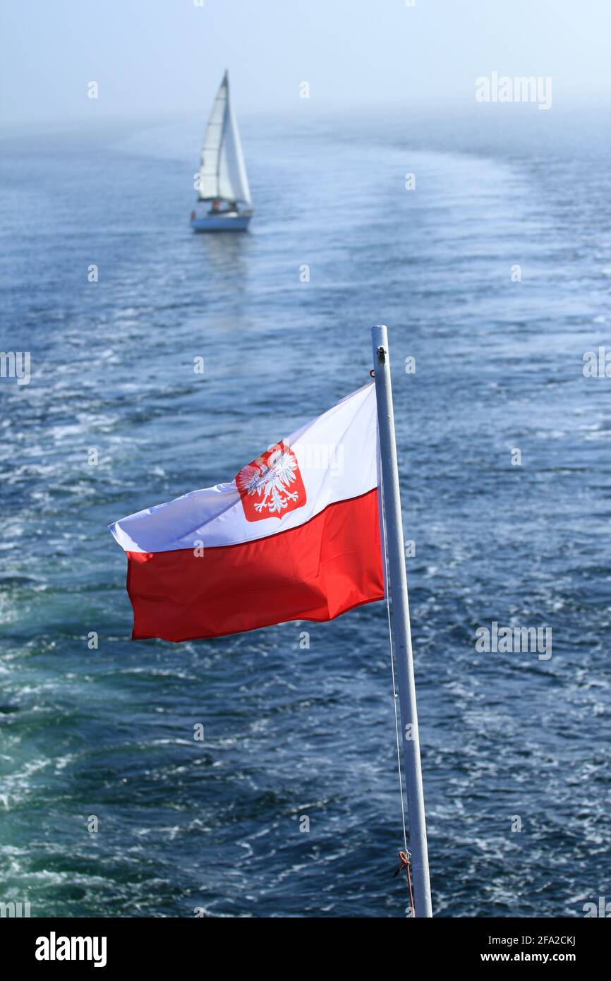 Bandiera polacca che sventolava sull'albero di una nave a. mare con uno yacht sullo sfondo Foto Stock