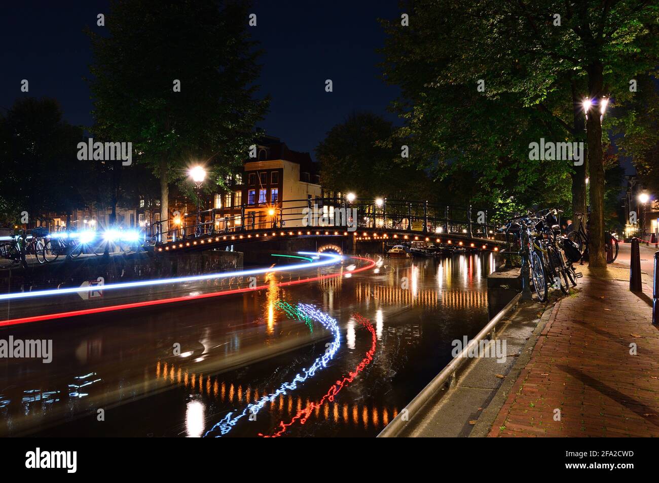 Una notte ad Amsterdam. Strisce chiare di una barca che scorre lungo il canale. Estate. Foto Stock