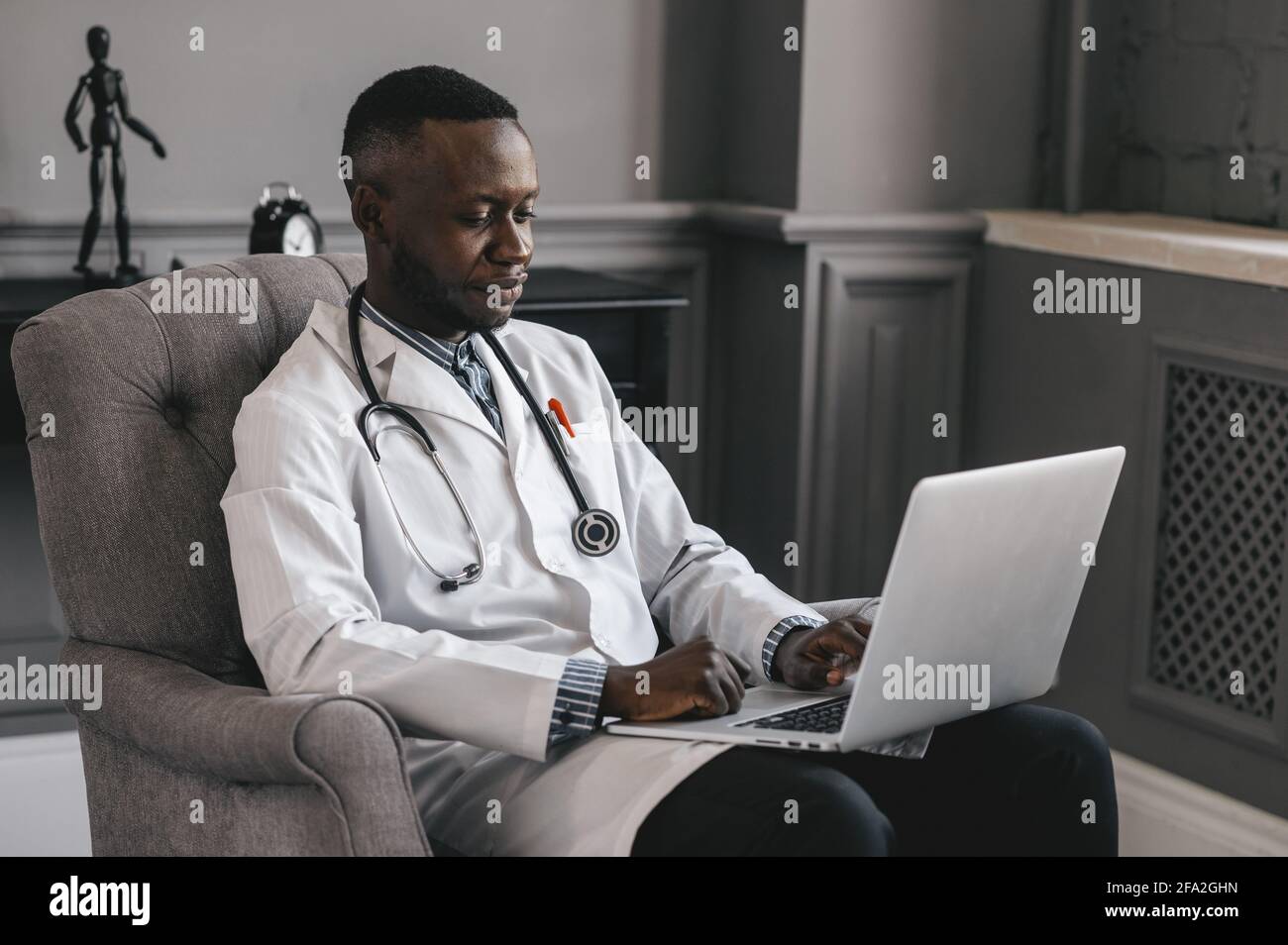 Medico dalla pelle scura che parla con Skype zoom con un computer portatile Foto Stock