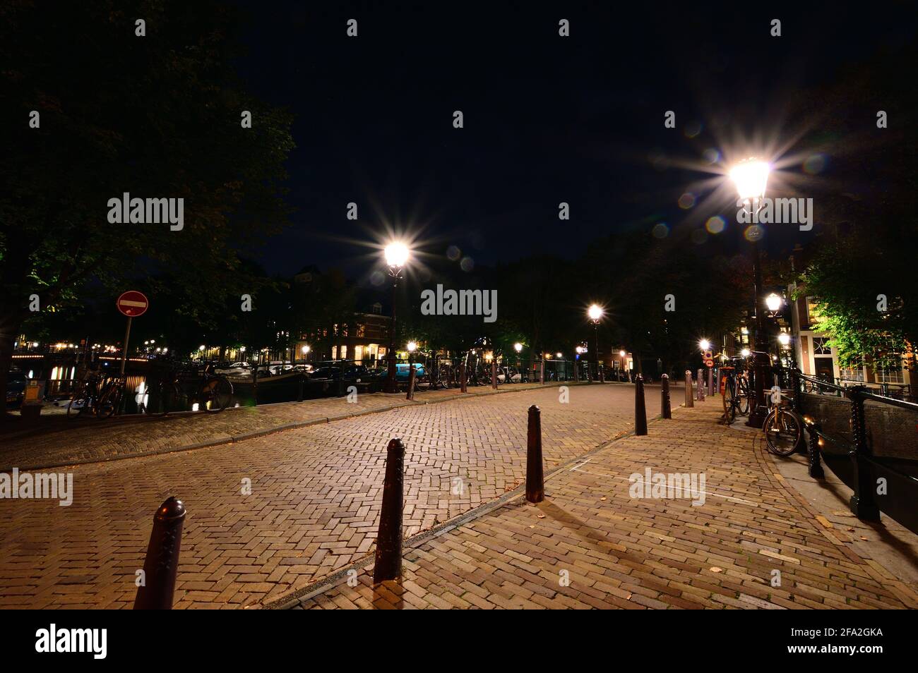 Una notte ad Amsterdam. Strada acciottolata illuminata da lampioni. Estate. Foto Stock