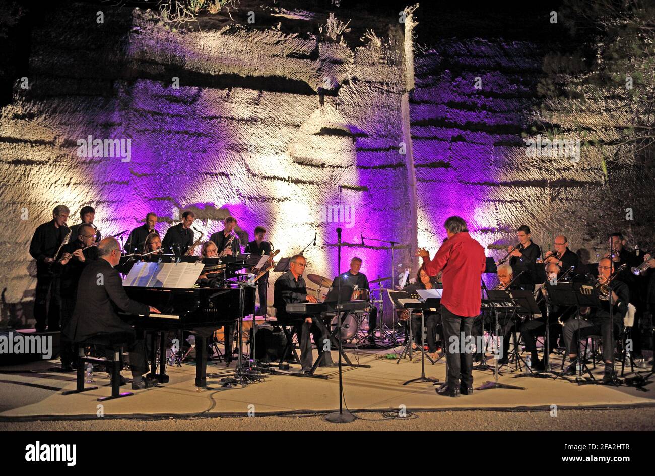 Un direttore d'orchestra e un'orchestra jazz sul palco all'aperto Carrieres du Bon Temps, cave di Junas, Gard, Francia Foto Stock