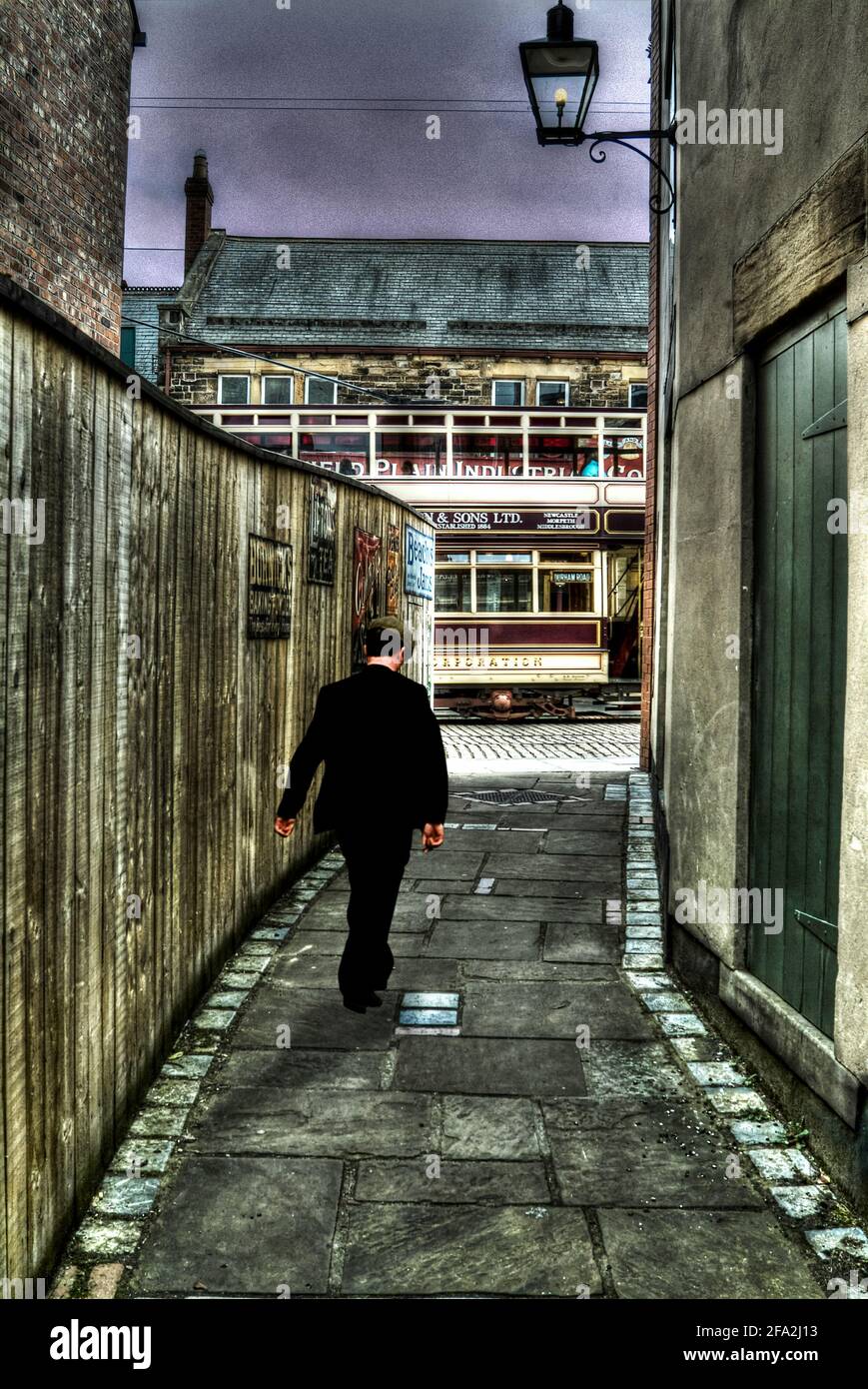 Uomo con cappello piatto che cammina nel vicolo Foto Stock