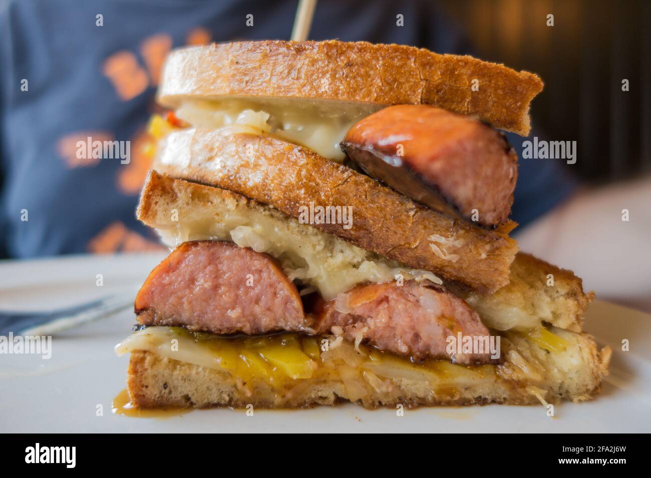 Delizioso sandwich alla griglia con salsiccia, formaggio e crauti. Foto Stock