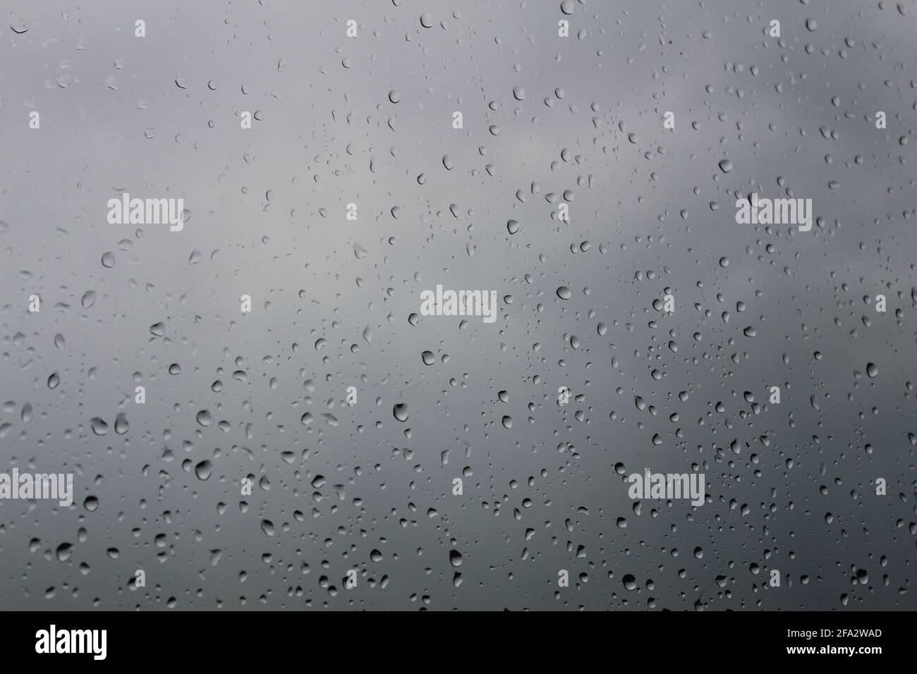 Gocce di pioggia sulla finestra con sfondo nuvoloso Foto Stock