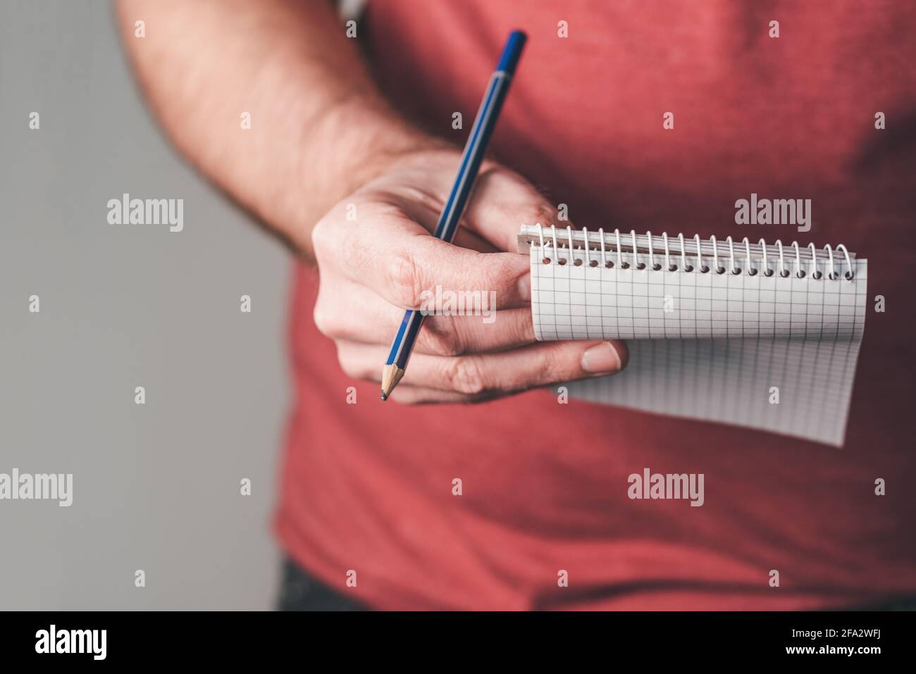 primo piano di una persona che tiene un piccolo blocco note a spirale e una matita dentro una mano Foto Stock