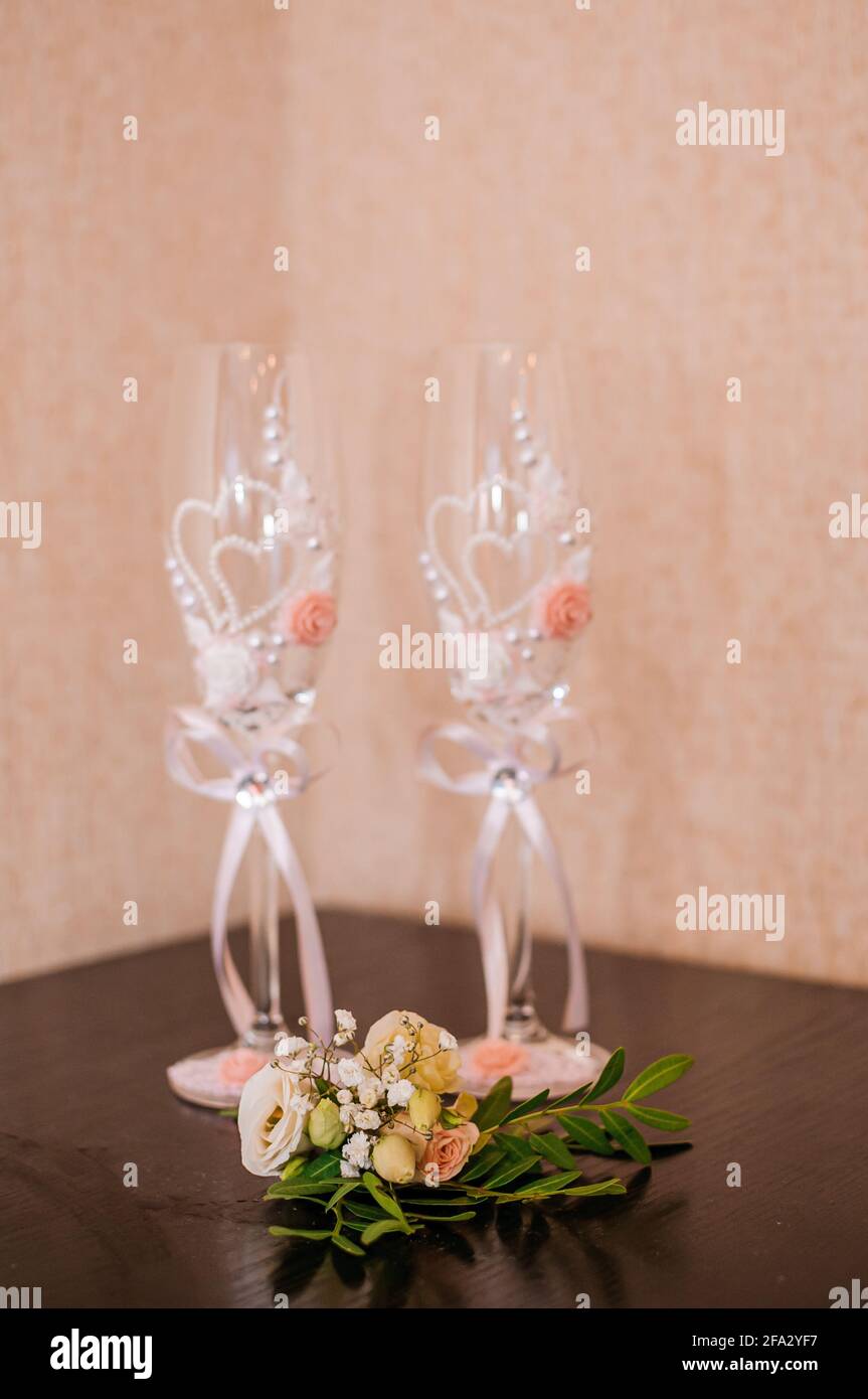 Bicchieri di champagne e boutonniere dello sposo su sfondo marrone Foto Stock