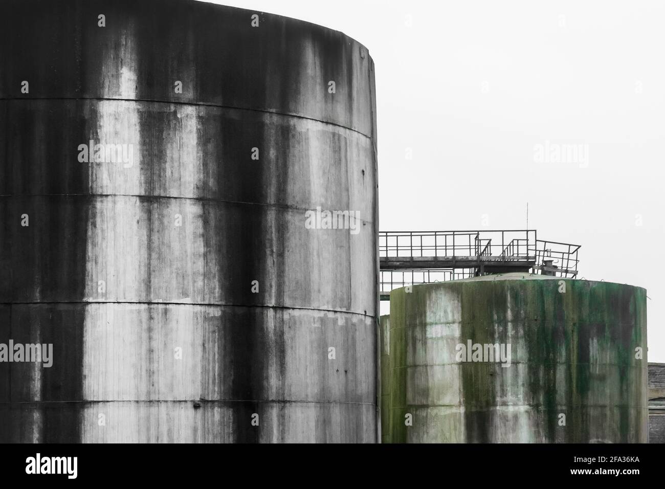 Vecchi serbatoi dell'olio combustibile con macchie di olio combustibile in un impianto industriale abbandonato. Foto Stock