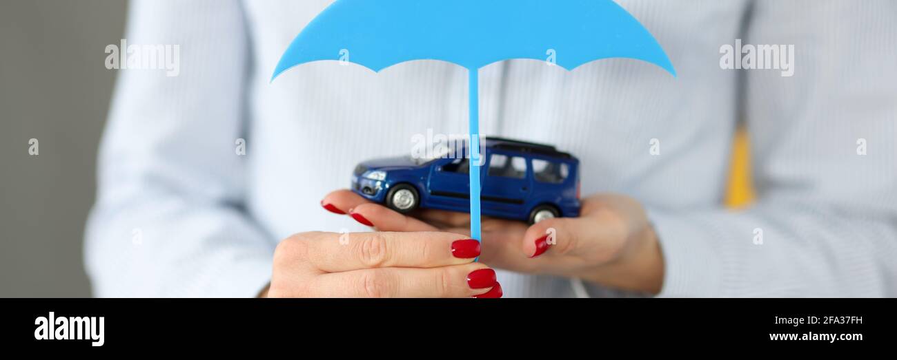 Le mani femminili tengono l'automobile giocattolo e l'ombrello vicino Foto Stock