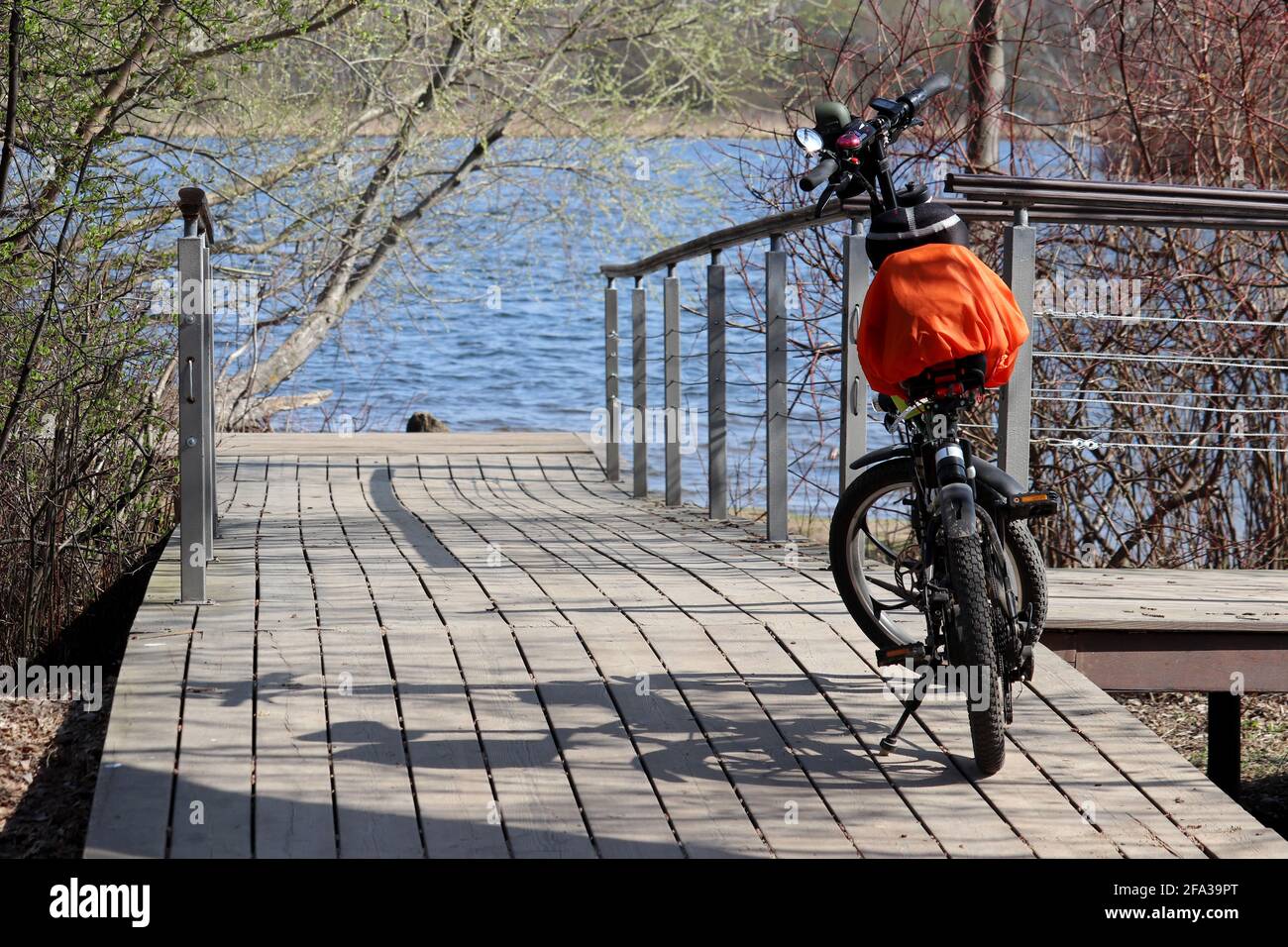 Bicicletta parcheggiata sulla riva del fiume in primavera. Viaggio sulla natura e il tempo libero in un parco Foto Stock