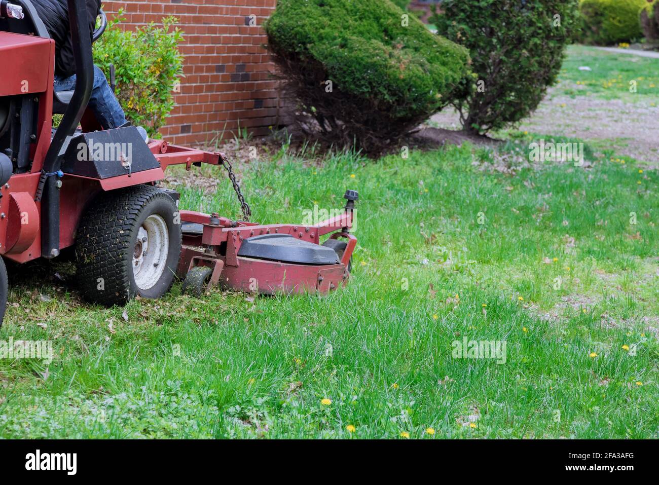 Rasaerba in funzione su prato verde con erba tagliata attrezzatura per la cura del giardino Foto Stock
