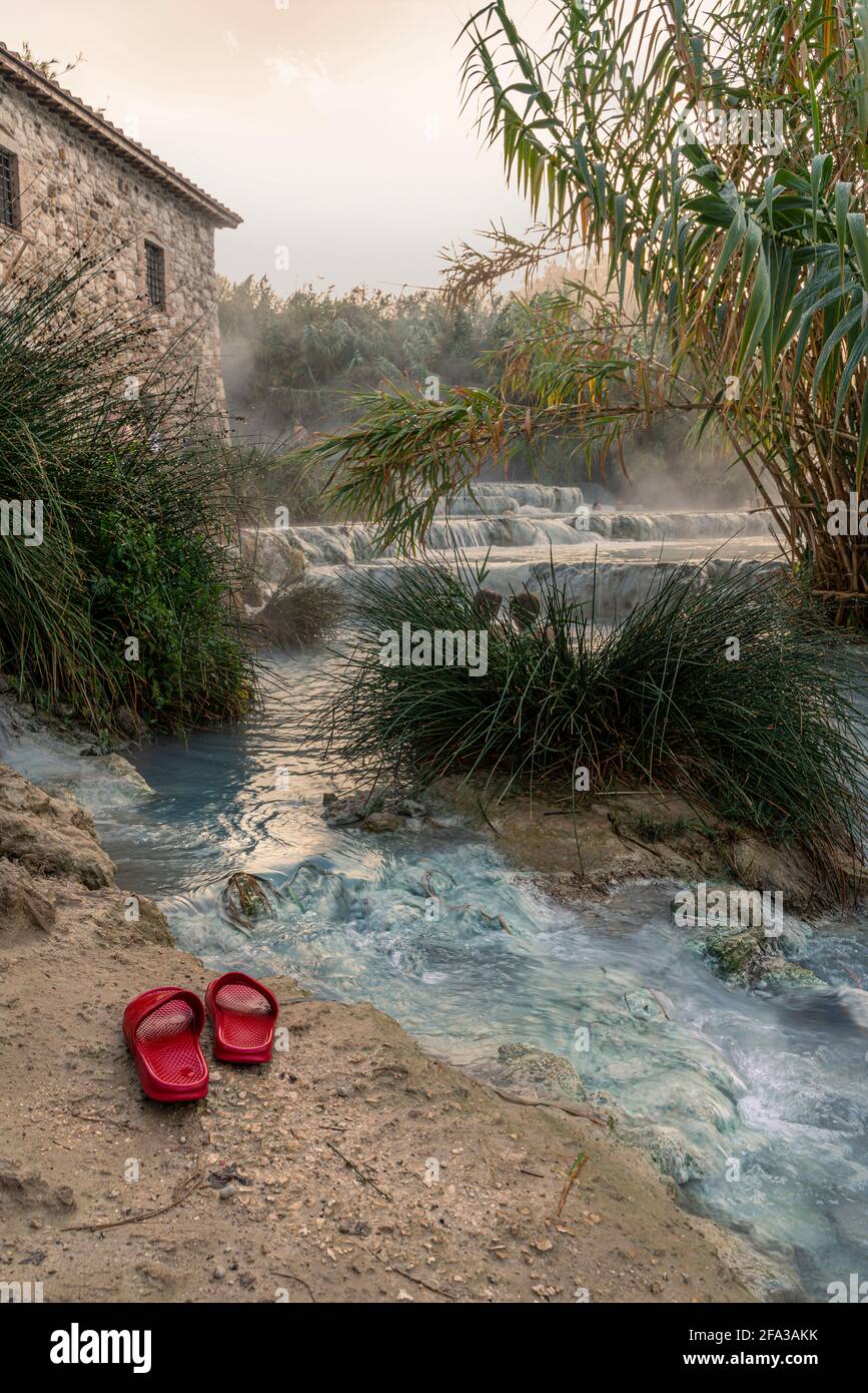Cascate del Mulino, due pantofole rosse lasciate ai margini delle piscine naturali di acqua termale. Saturnia, Grosseto, Toscana, Italia, Europa Foto Stock