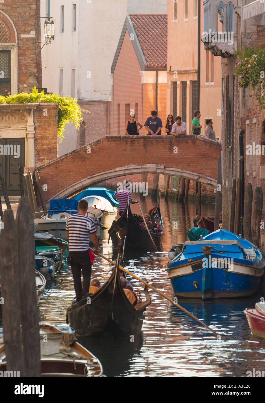 Venezia, Provincia di Venezia, Regione Veneto, Italia. Persone sul ponte guardando gondole in avvicinamento. Venezia e la sua laguna sono patrimonio dell'umanità dell'UNESCO Foto Stock