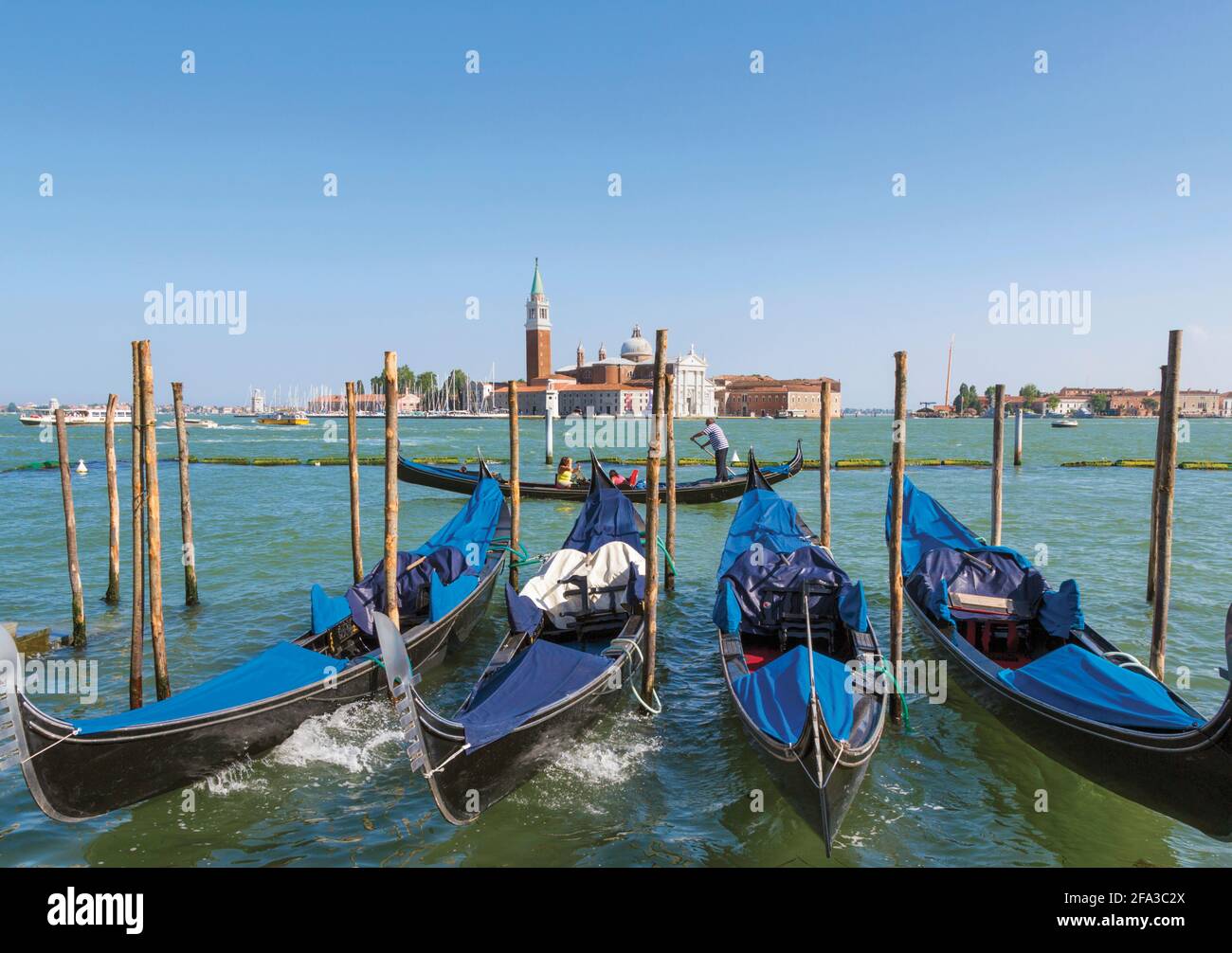 Venezia, Provincia di Venezia, Regione Veneto, Italia. Gondole ormeggiate nel Bacino di San Marco. San Giorgio maggiore alle spalle. Venezia e la sua laguna sono una Foto Stock