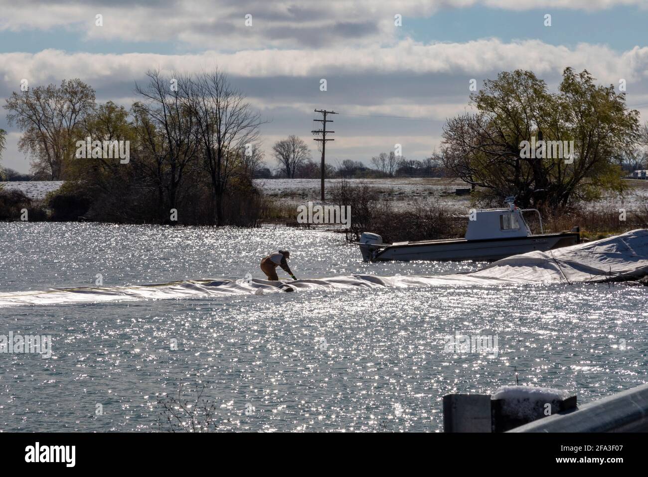 Detroit, Michigan - UN lavoratore installa una diga temporanea per proteggere Belle Isle, un parco insulare nel fiume Detroit, dalle inondazioni. Leve di acqua alta Foto Stock